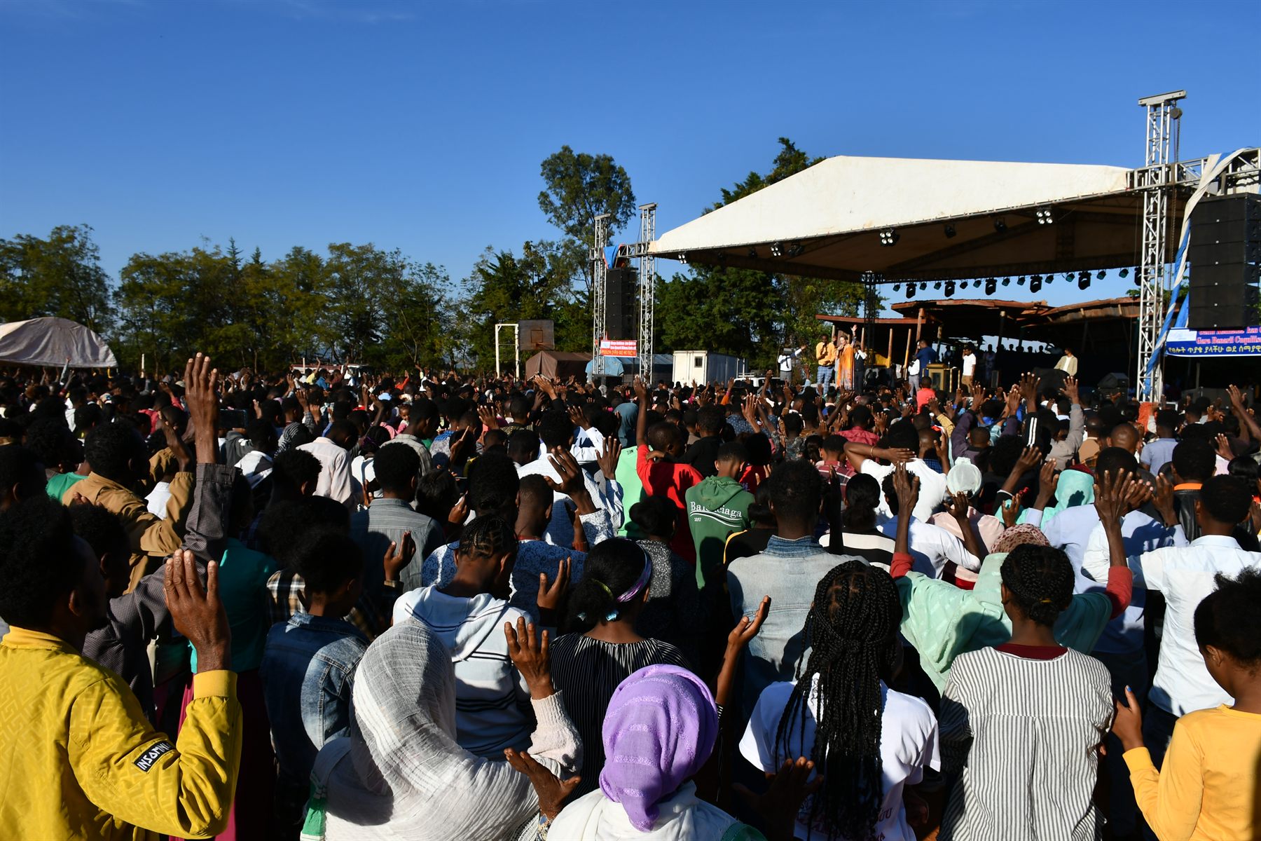 Open-air Gospel crusade crowd with hands raised